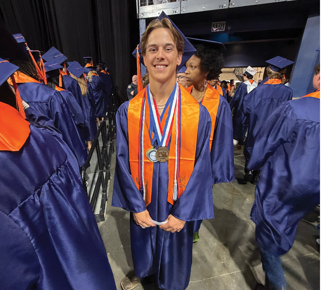 A man wearing a blue graduation gown and a gold medal stands in front of a crowd of people. Contenido generado con IA