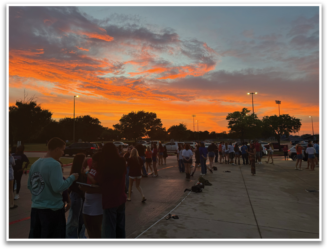 A group of people are standing outside at a park, watching a beautiful sunset. Contenido generado con IA