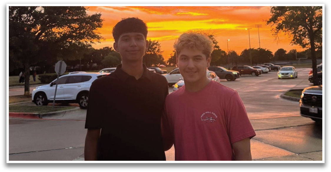Two young men standing on a sidewalk, posing for a picture with a beautiful sunset in the background. Contenido generado con IA