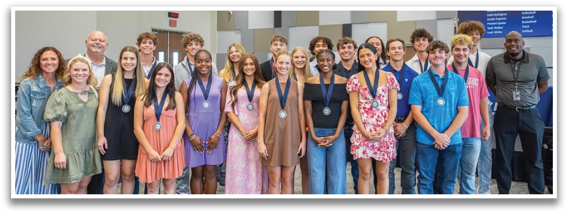 A group of people, both male and female, are standing together in a room. They are wearing medals, indicating that they have likely participated in a competition or event. The group consists of individuals of various heights and positions, all standing close to each other. Contenido generado con IA