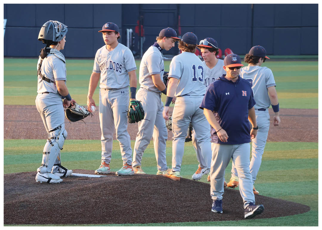 Two men are standing on a baseball field, engaged in conversation. One man is wearing a baseball uniform, while the other is not. Contenido generado con IA
