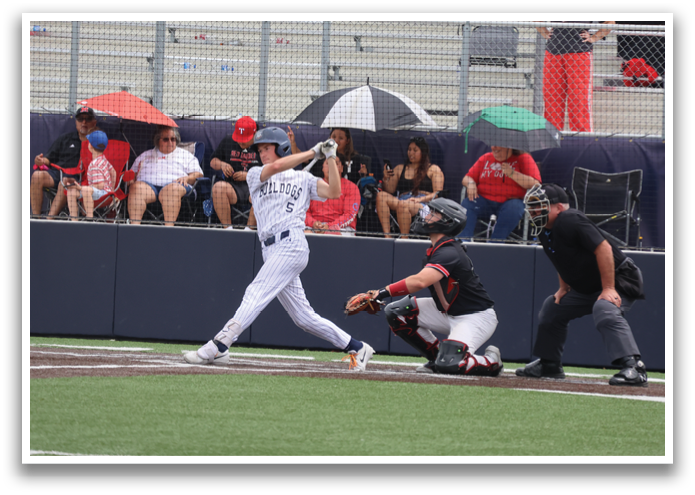 A baseball player is swinging a bat, while a catcher and an umpire watch. The batter is wearing a white uniform and a red helmet. There are several people in the background, some of whom are holding umbrellas. Contenido generado con IA