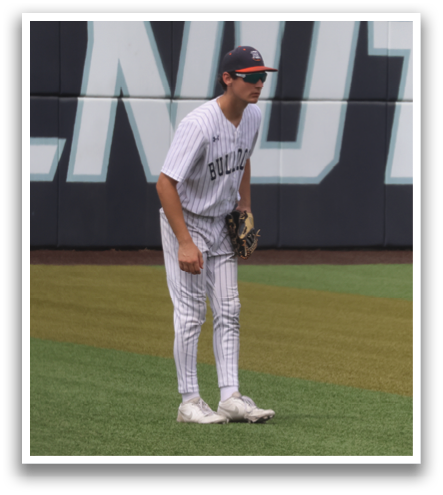 A baseball player stands on a field in front of a black and white sign. Contenido generado con IA