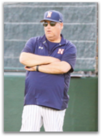 A man wearing a blue shirt and sunglasses is standing on a baseball field. Contenido generado con IA