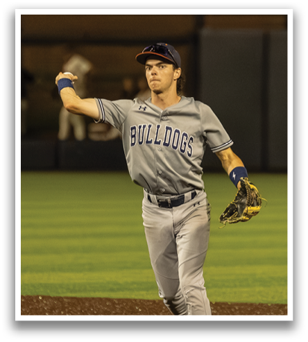 A baseball player in a grey uniform is standing on the field, extending his arm out. Contenido generado con IA