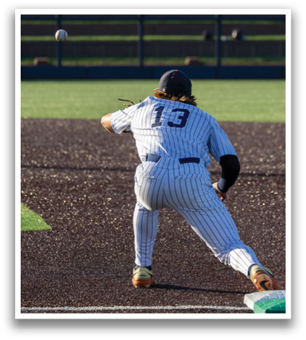 A baseball player in a blue and white uniform is running towards a base, attempting to reach it before the ball arrives. Contenido generado con IA