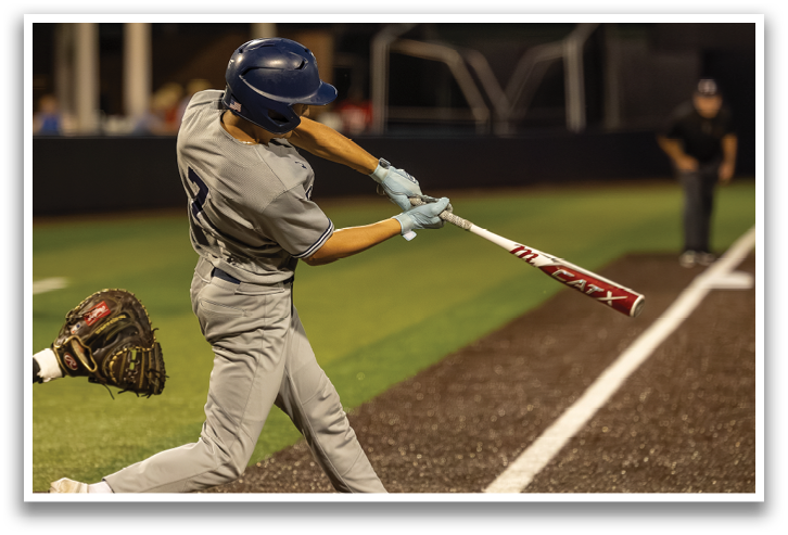 A baseball player in a grey uniform is swinging a bat at a ball. Contenido generado con IA