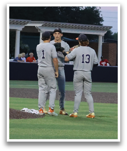 Two baseball players wearing grey uniforms are standing on the field, talking to each other. Contenido generado con IA