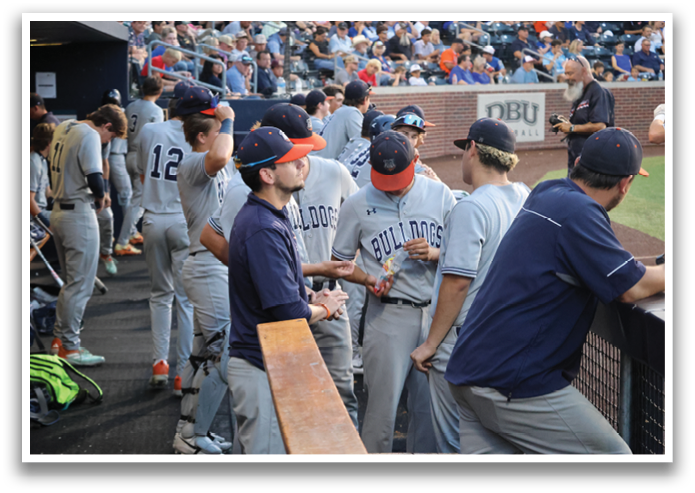 Baseball players in a dugout, some sitting on benches and others standing. Contenido generado con IA
