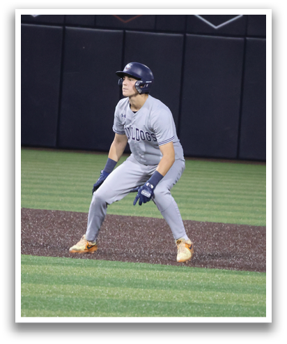 A baseball player is standing on the field wearing a grey shirt and blue gloves. Contenido generado con IA