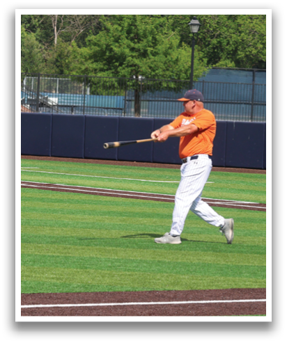 A man in an orange shirt is swinging a baseball bat on a baseball field. Contenido generado con IA