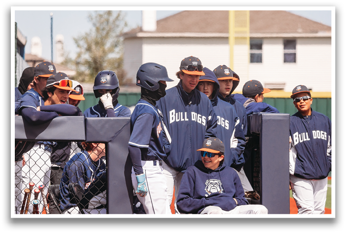A group of baseball players wearing blue and white uniforms are standing around a fence. Contenido generado con IA