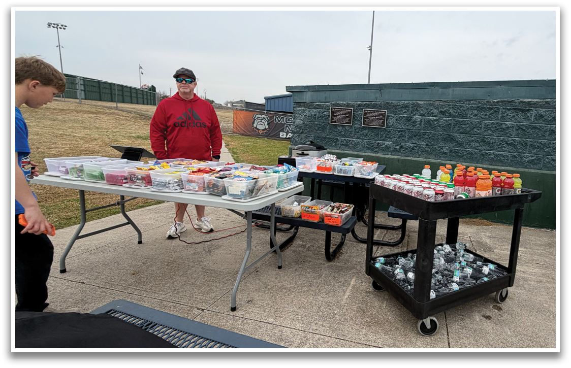 A table filled with food and drinks is set up on a sidewalk. Contenido generado con IA