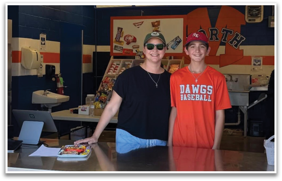 A man and a woman stand in a food court, both wearing sunglasses. The woman is wearing a black shirt and the man is wearing a red shirt. Contenido generado con IA