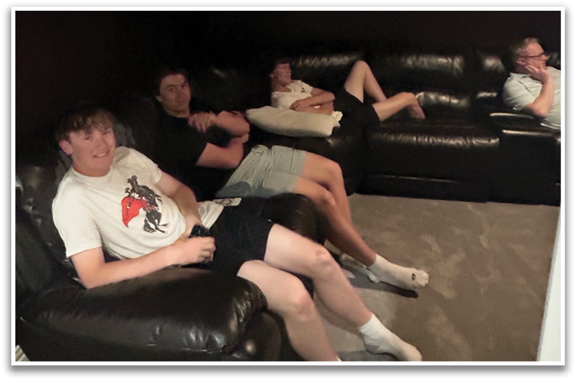 Four people are sitting on a couch in a dark room. Contenido generado con IA