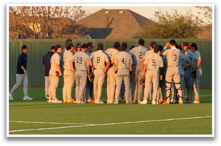 Baseball players in uniforms on a field, some standing and some sitting, with a man in a blue shirt talking to them. Contenido generado con IA