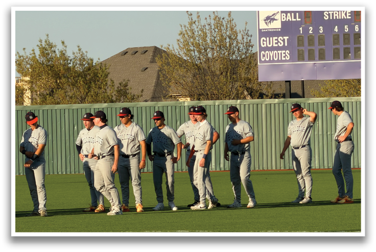 A group of baseball players standing on a field in front of a scoreboard. Contenido generado con IA