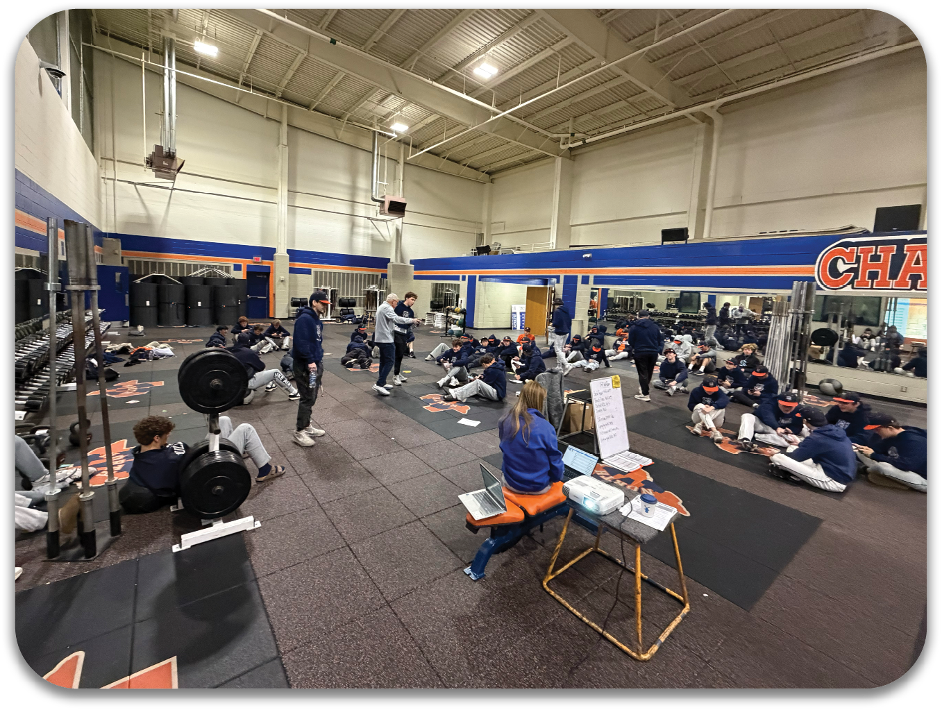 A group of people are sitting and standing in a gym. Contenido generado con IA