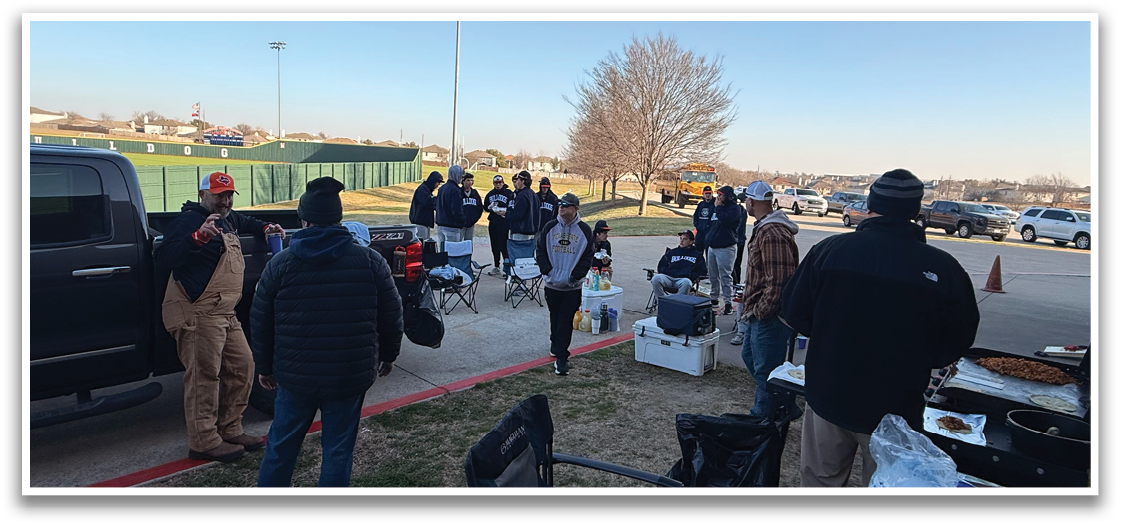 A group of people are gathered around a table with food and drinks. There are several chairs and a truck nearby. Contenido generado con IA