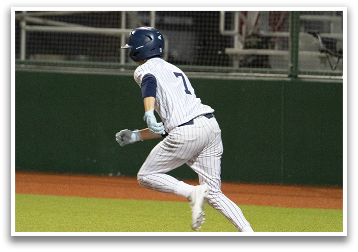 A baseball player wearing a blue helmet and white uniform is running towards a base. Contenido generado con IA