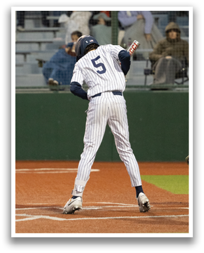 A baseball player in a blue and white uniform is swinging a bat on a baseball field. Contenido generado con IA