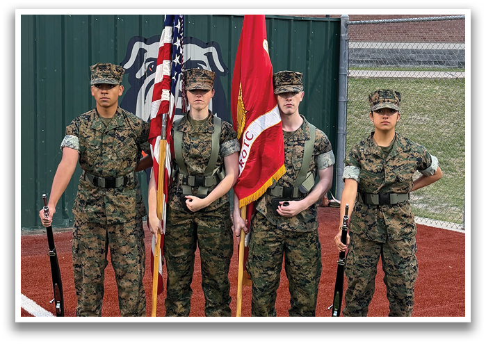 Four soldiers in camouflage uniforms are standing on a field, holding flags. Contenido generado con IA