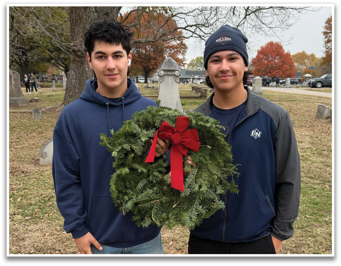 Two men are standing next to a grave marker, one of them holding a wreath. Contenido generado con IA