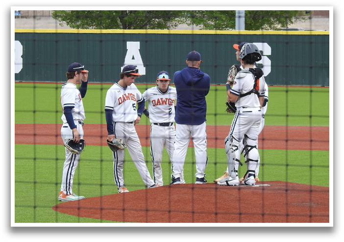 Four baseball players on a field, two of them wearing catchers gear, talking to an umpire. Contenido generado con IA