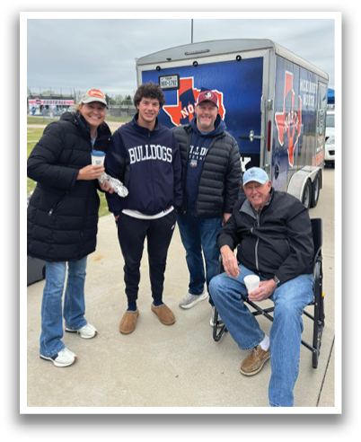 Four people are standing in front of a trailer, posing for a picture. Contenido generado con IA