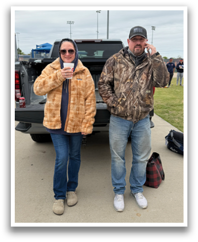 Two people standing next to a truck, one of them wearing a camouflage jacket and the other wearing a hat. Contenido generado con IA