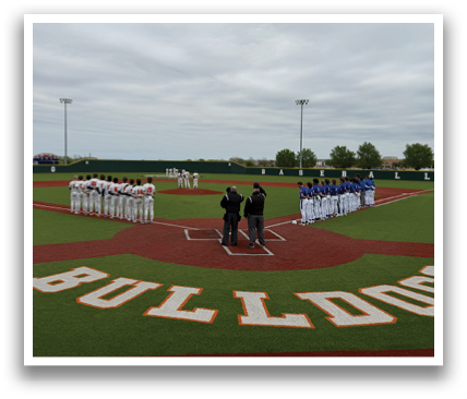 A group of baseball players are standing on a field, some of them wearing blue and white uniforms. They are lined up in front of the pitcher's mound, waiting for the game to begin. Contenido generado con IA