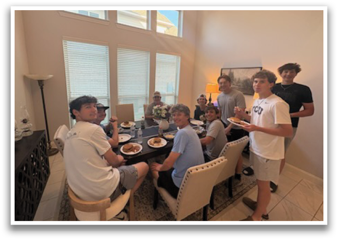 A group of people are sitting around a dining table, enjoying a meal together. Contenido generado con IA