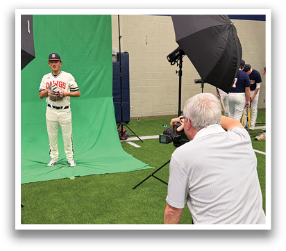A man is taking a picture of a baseball player in a field. Contenido generado con IA
