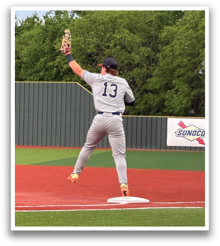 A baseball player is standing on a field, wearing a grey uniform and a blue hat. He is holding a baseball glove and appears to be ready to catch a ball. Another person is standing nearby, possibly a teammate or an opponent. The scene takes place on a baseball field, with a baseball glove visible in the foreground. Contenido generado con IA