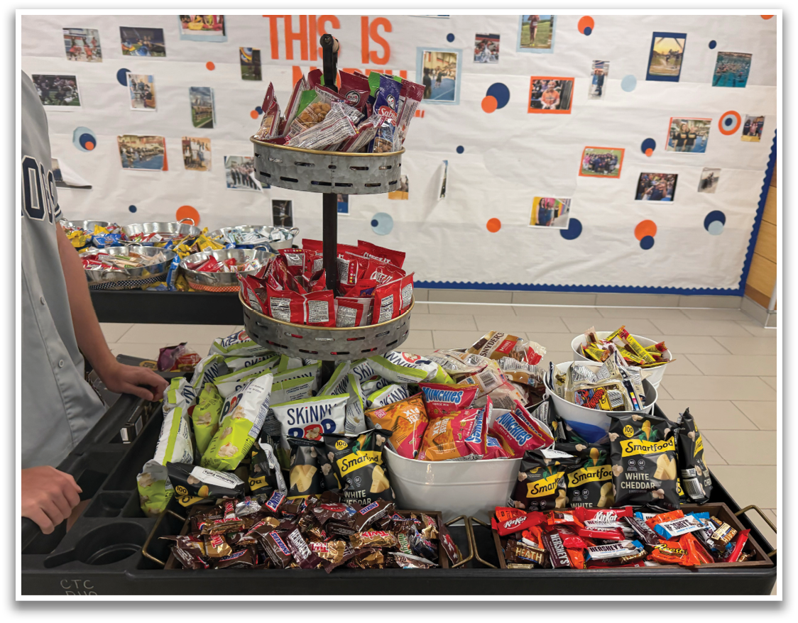 A table full of snacks and drinks with a boy standing next to it. Contenido generado con IA