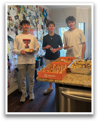 Three young men are standing in a kitchen, holding plates of food. Contenido generado con IA