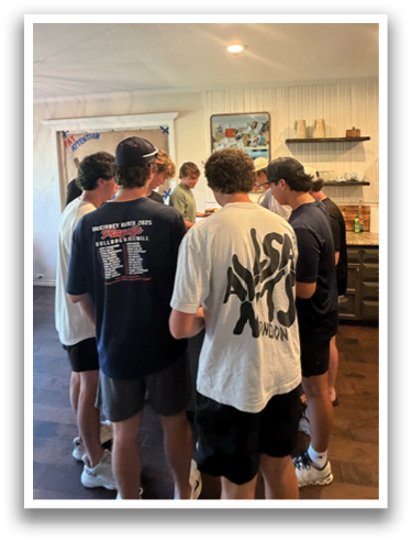 A group of people are standing in a kitchen, looking at a man who is holding a cell phone. Contenido generado con IA