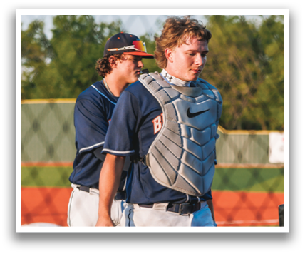 Two baseball players wearing blue uniforms and helmets are standing on a field. One of the players is holding a baseball glove. Contenido generado con IA