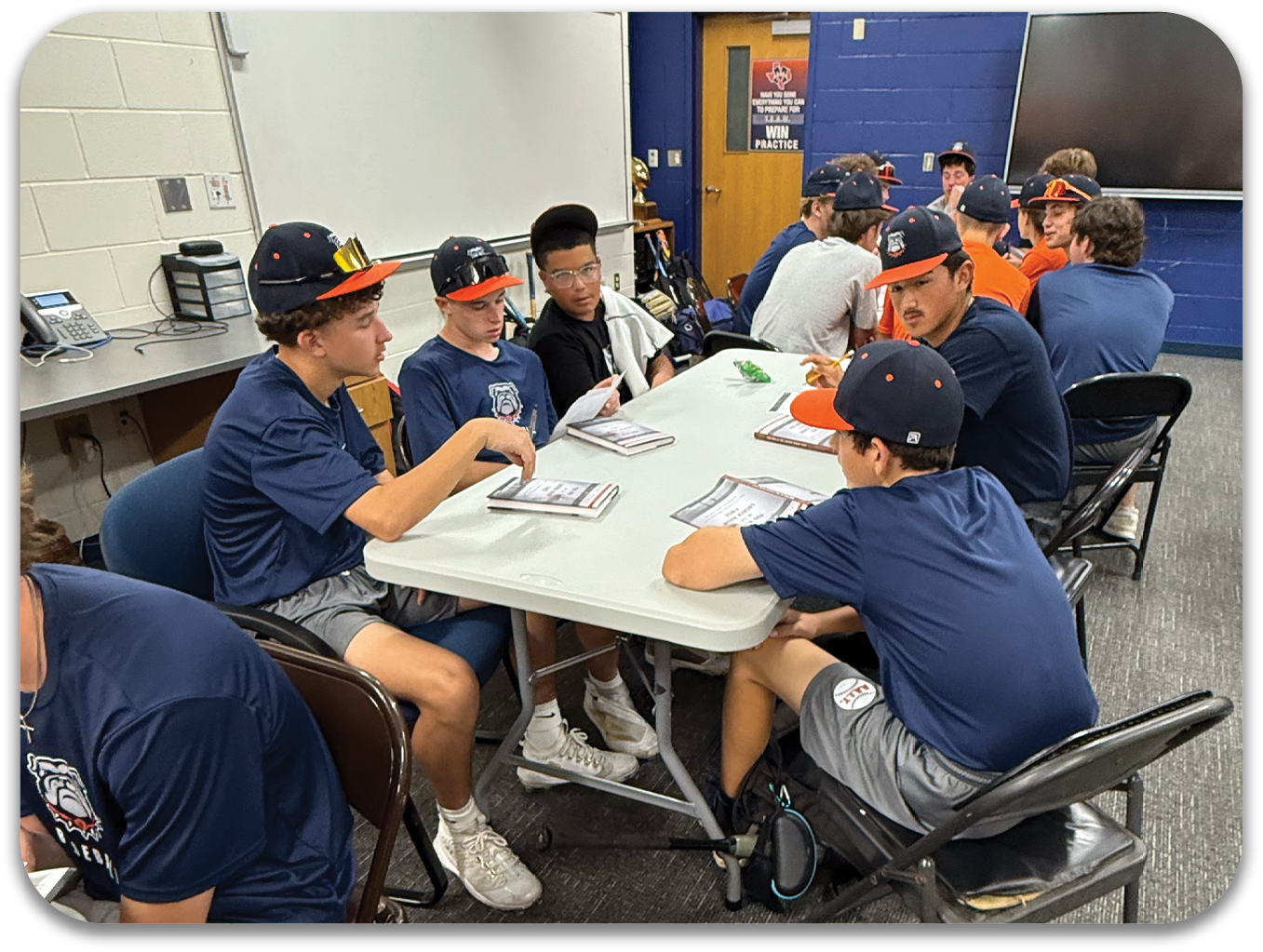 A group of men are sitting around a table in a room, engaged in conversation. Contenido generado con IA