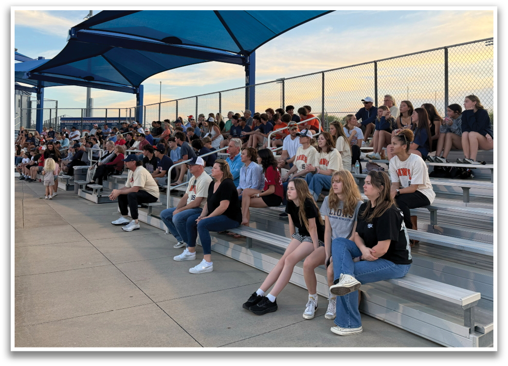 A crowd of people are sitting on a bench at a baseball game. Contenido generado con IA