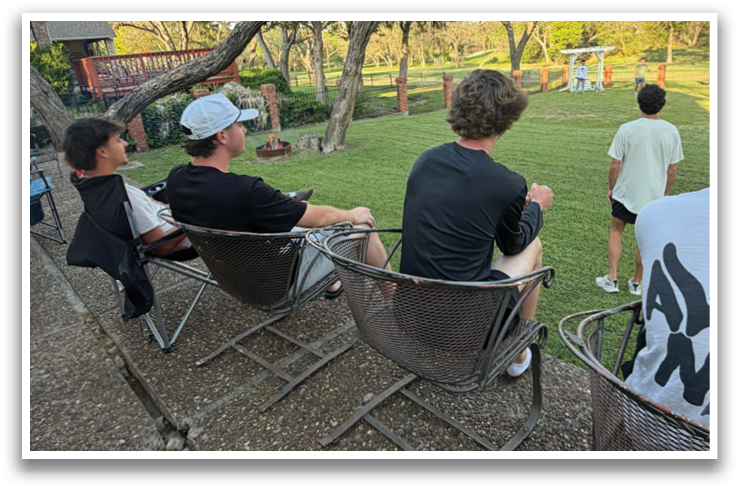 Four people are sitting in chairs outside, watching a game. Contenido generado con IA