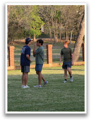 Three men are standing in a grassy field, playing with a tennis ball. Contenido generado con IA