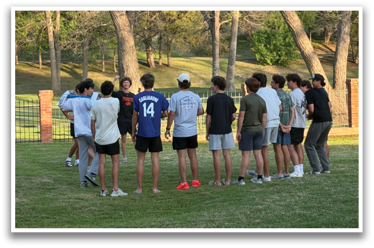 A group of young men are standing in a circle on a grassy field, engaged in a conversation. Contenido generado con IA