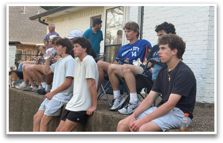 A group of people are sitting on a concrete wall, watching a baseball game. Contenido generado con IA