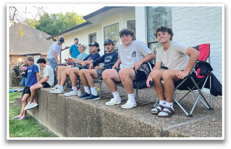 A group of young men are sitting on a concrete ledge outside a house. Contenido generado con IA