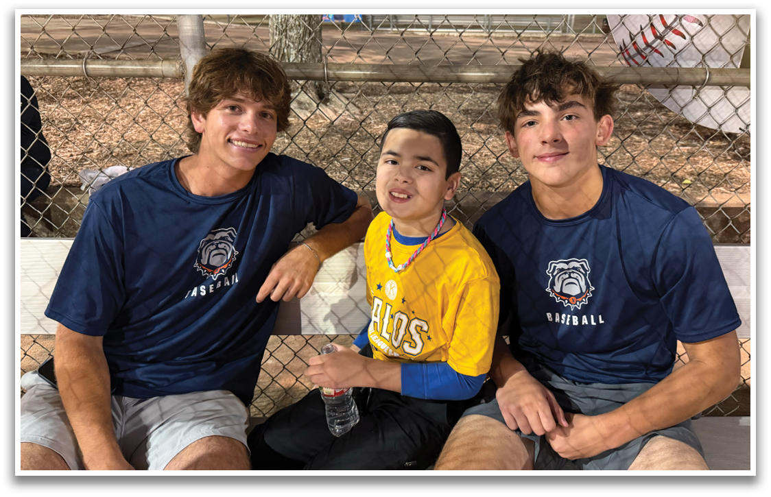 Three people are sitting on a bench. One is a young boy and the other two are men. They are all smiling. Contenido generado con IA