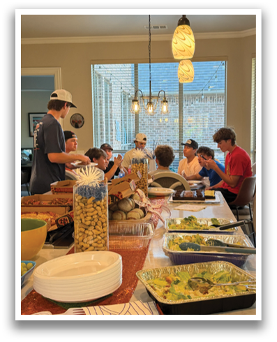 A group of people are gathered around a table filled with food. Contenido generado con IA