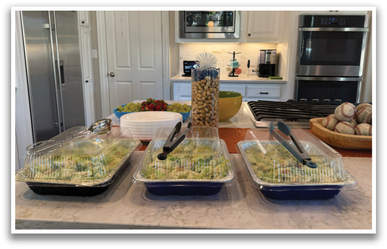 A kitchen counter with three containers of salad and a bowl of fruit. Contenido generado con IA