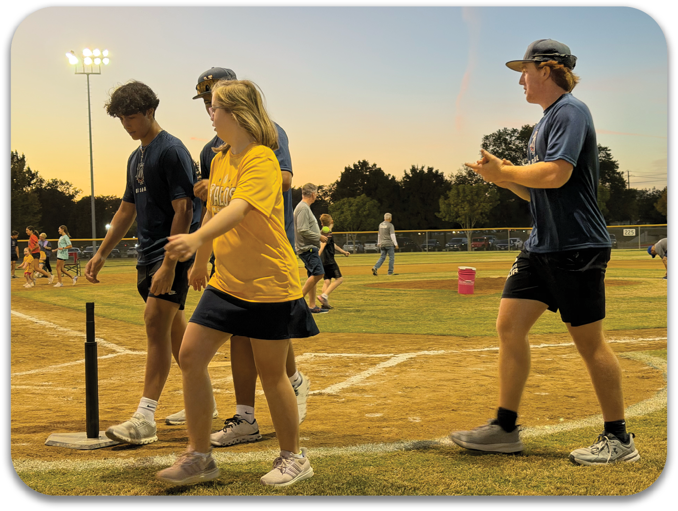 A group of people, including a woman in a yellow shirt, are walking on a baseball field. Contenido generado con IA