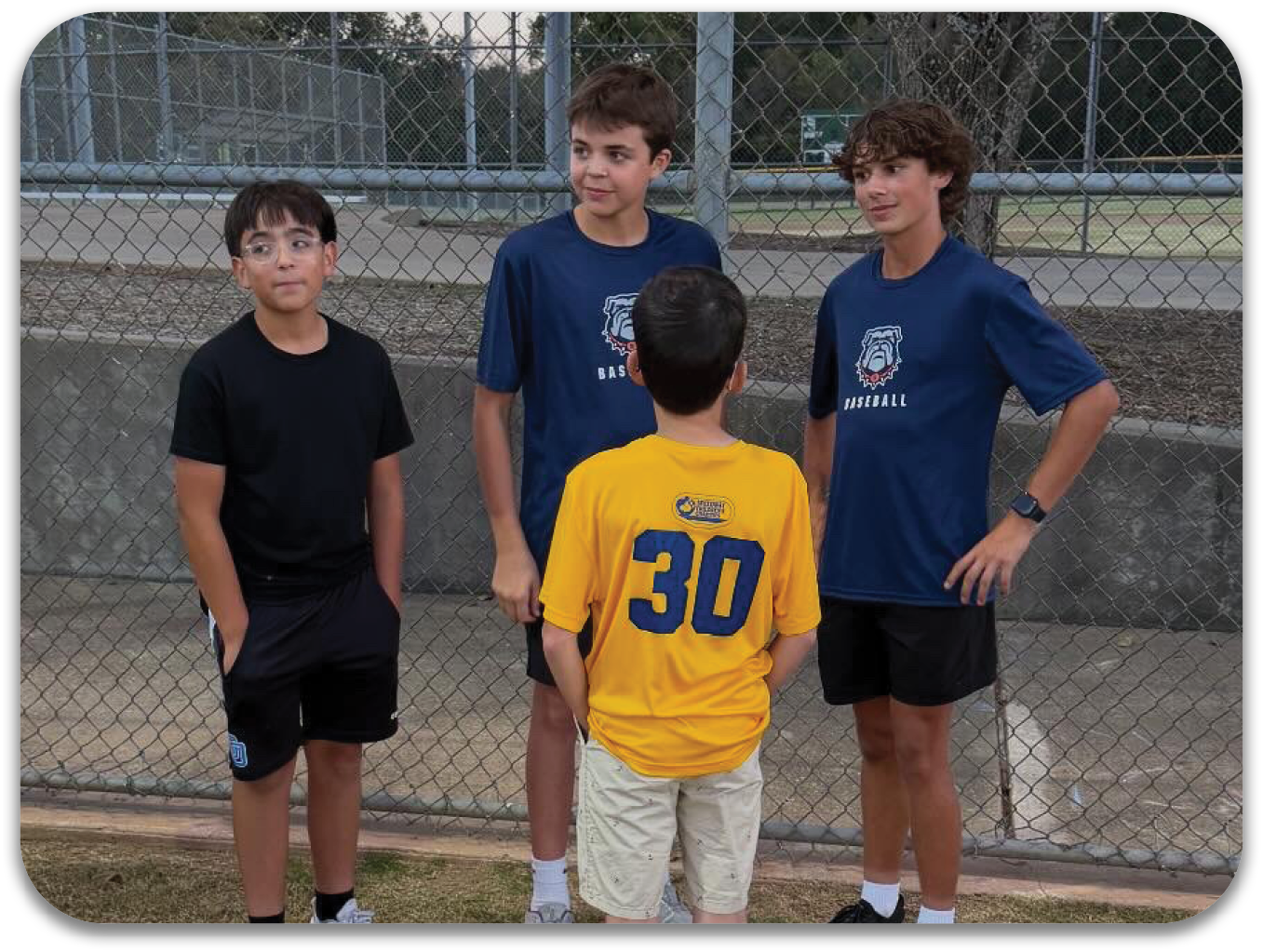 Four young boys wearing baseball uniforms are standing together on a field. Contenido generado con IA